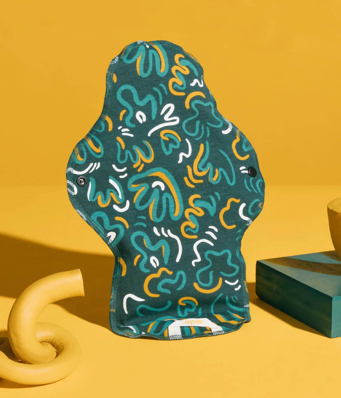 Aisle reusable period pad in a teal and yellow pattern.