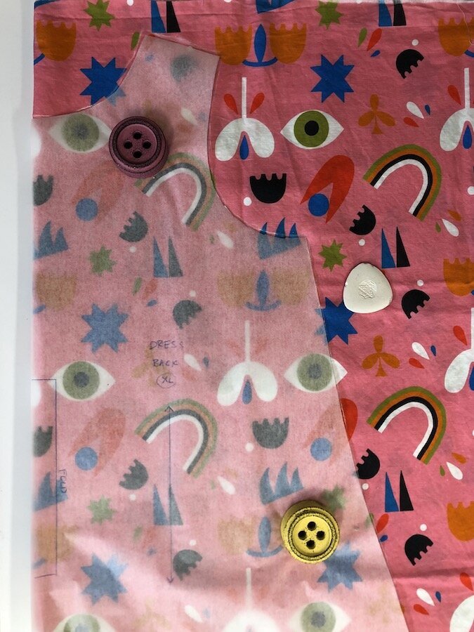 A piece of pink patterned fabric that's been cut. 