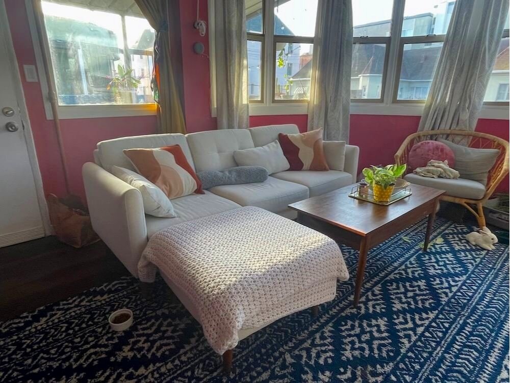 White burrow couch with ottoman, set up in a pink living room.