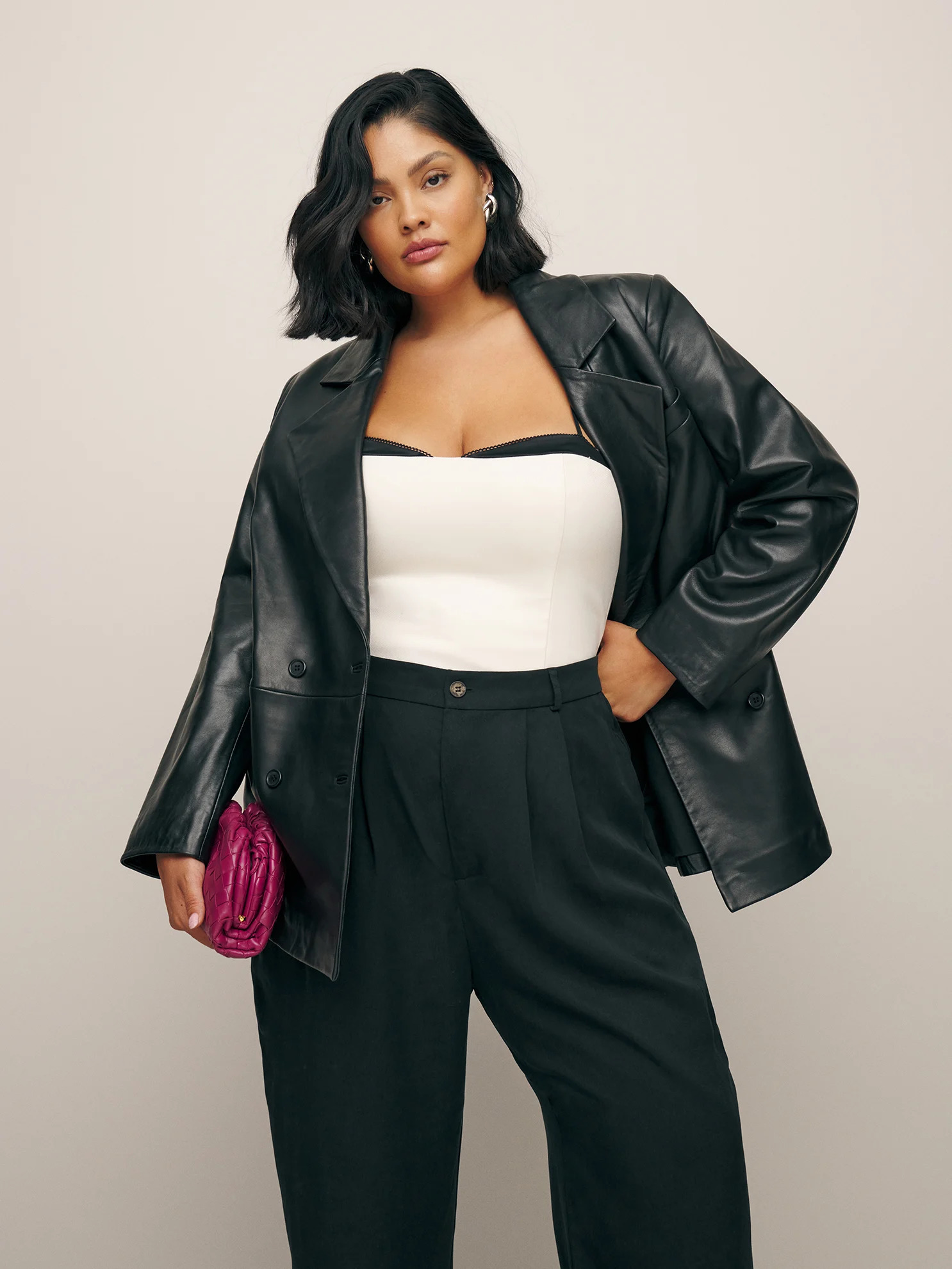 A model wearing a leather blazer and black dress pants from Reformation.