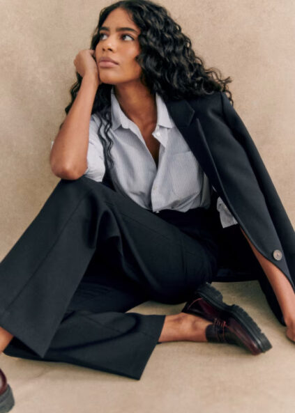 A model wearing a black women's pantsuit from Sezane.