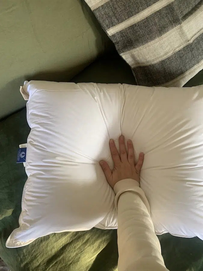 A hand pressing a sol organics pillow.