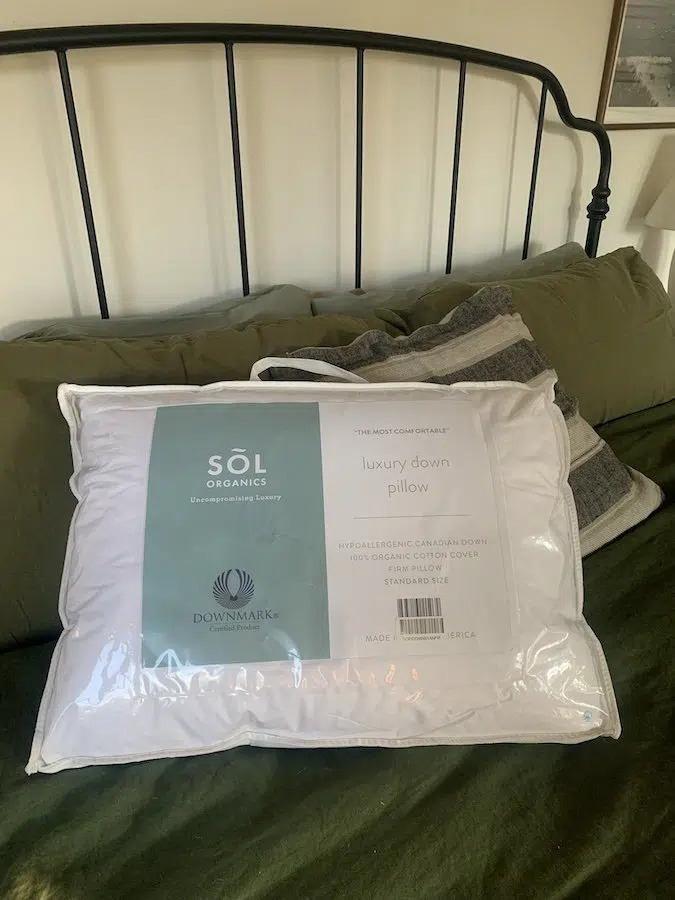 A sol organics pillow in its protective packaging on a neatly made bed.