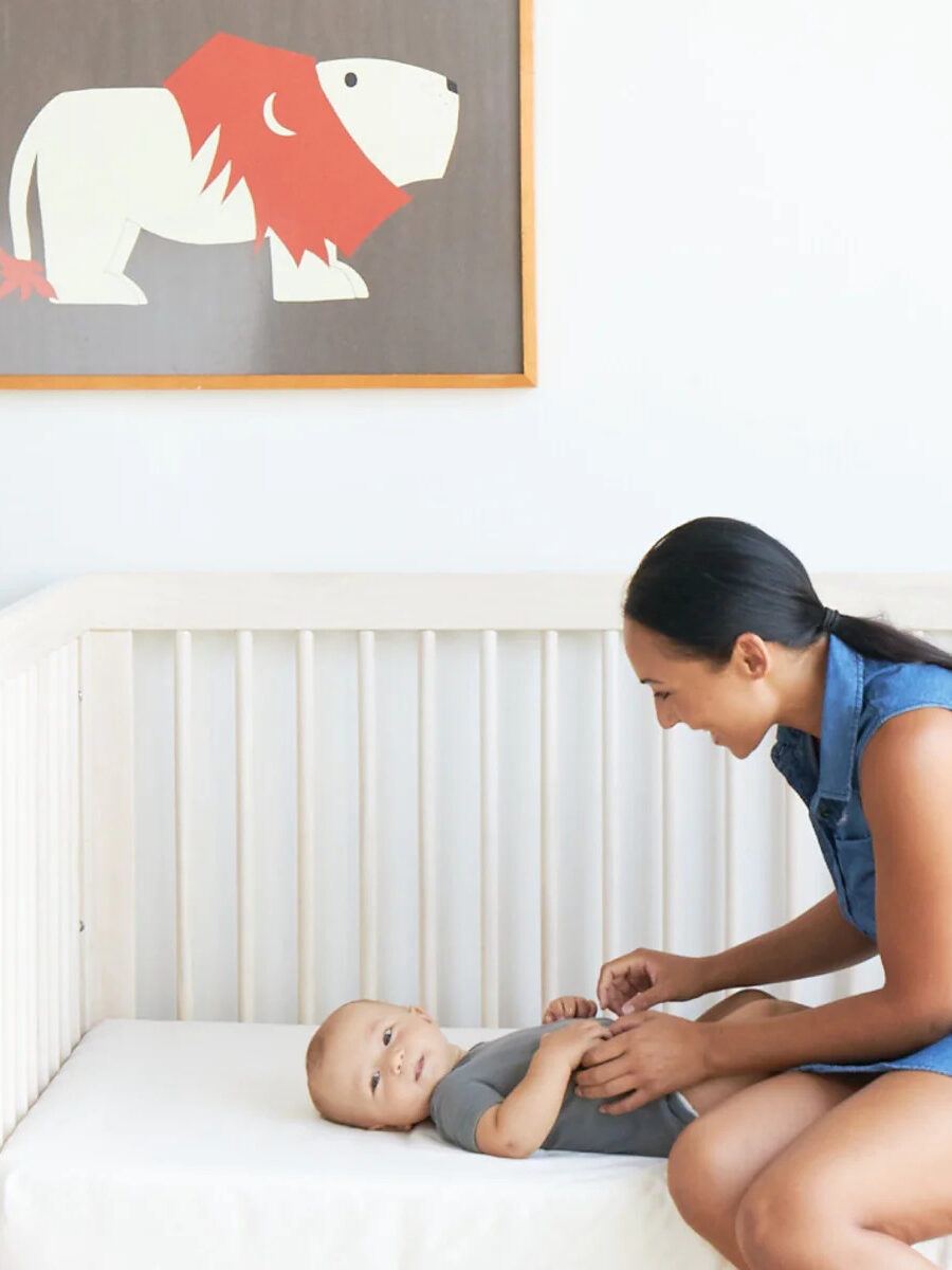 A woman plays with a baby on a Brentwood Home crib mattress.