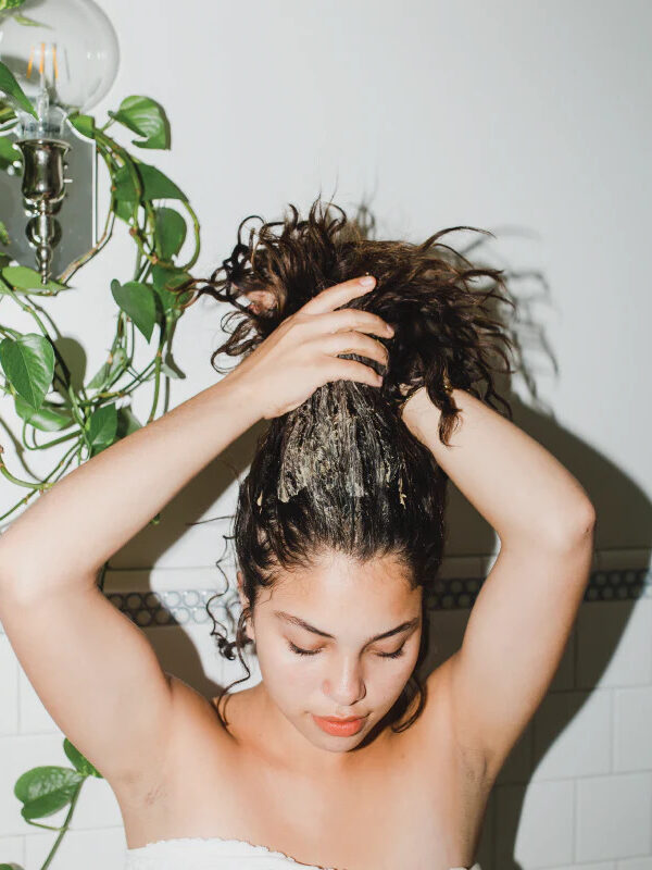 A model runs product through her curly hair. 