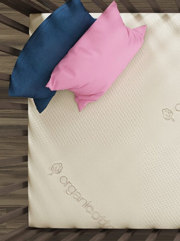 A shot looking down on a Saatva crib mattress and two pillows