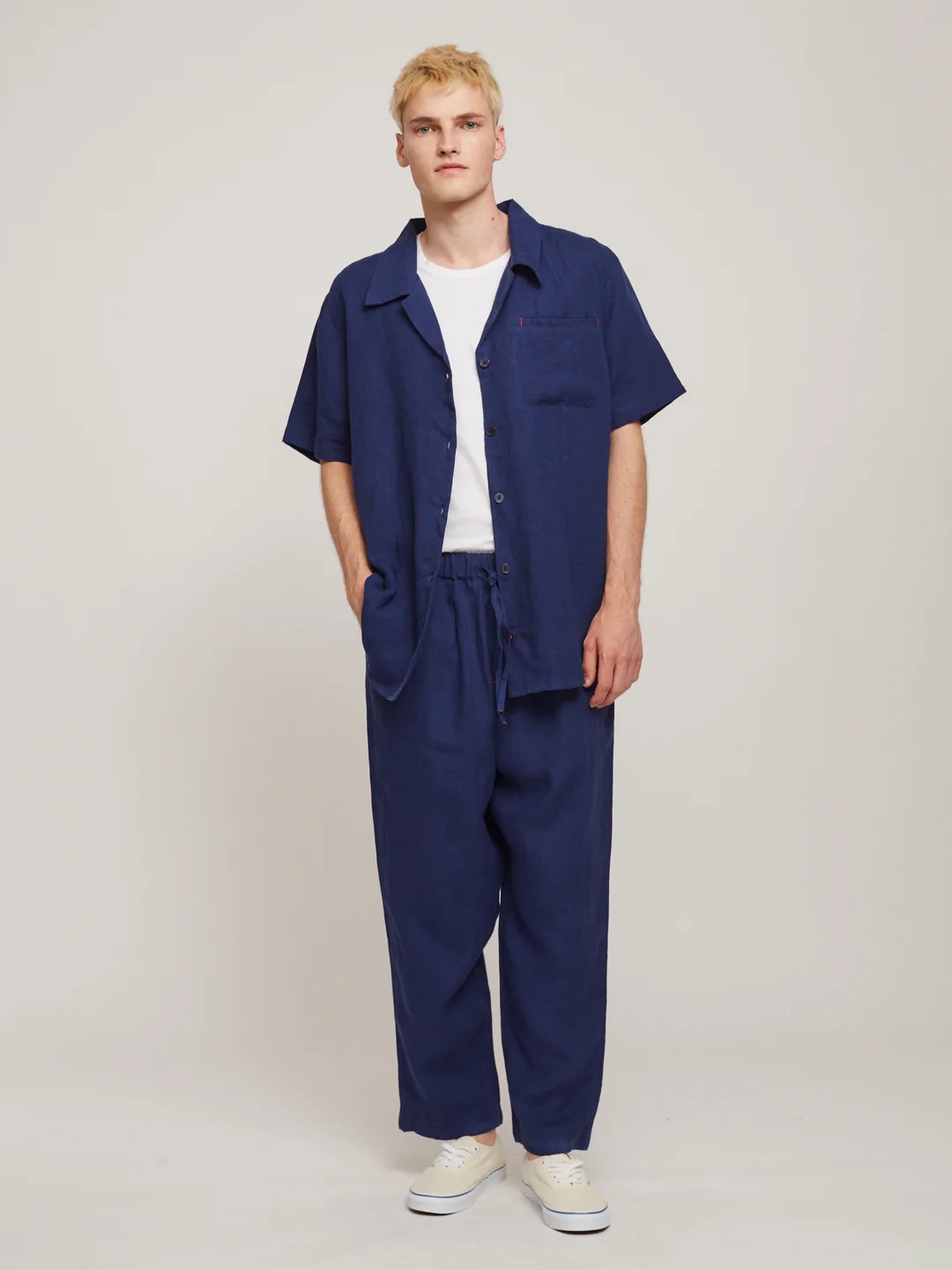 A model wears the blue linen joggers and matching top in a studio shot.