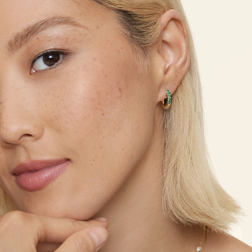 Woman with blond hair wearing brilliant earth emerald hoop earrings