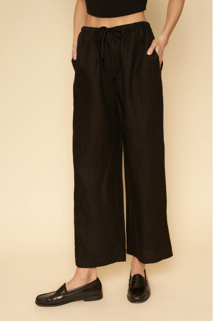 A model's legs in loose black linen pants.