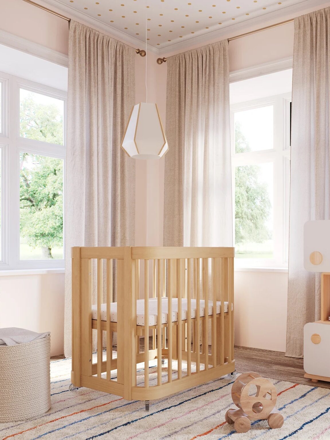A mini crib in a pink nursery.