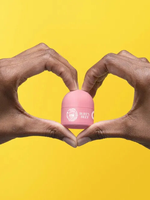 Two hands holding Burt's Bees Refillable Beeswax Lip Balm. 
