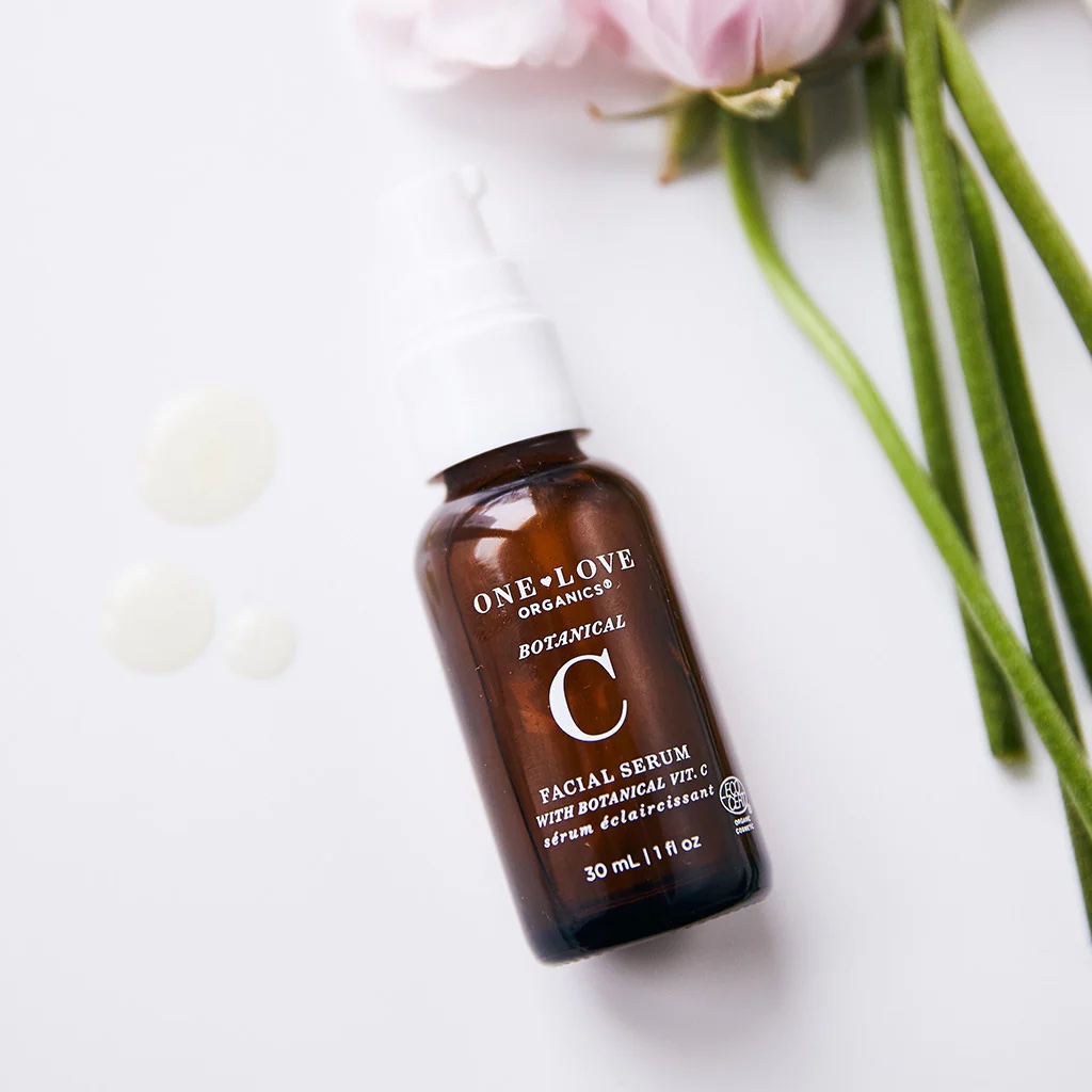 A bottle of the product on a table next to some flowers.