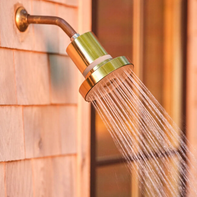 A detail of a gold Jolie filtered showerhead.