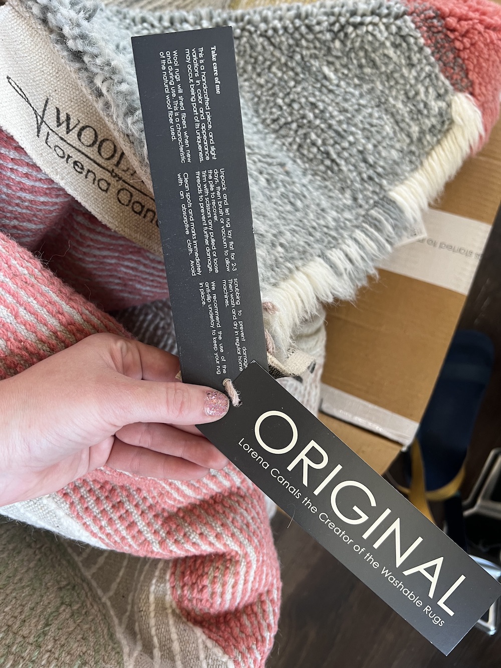 Close up of the tags on a Lorena Canals washable rug. The tag details the features of the rug and washing instructions. 