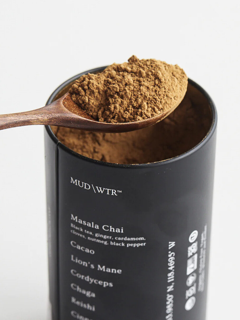 A wooden spoon removing a scoop of MudWtr coffee alternative from its container.