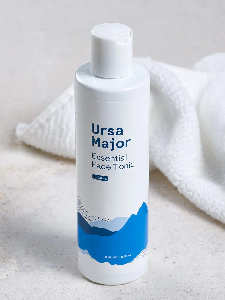 Ursa Major's Essential Face Tonic set on a grey counter with a crumpled white towel behind it.