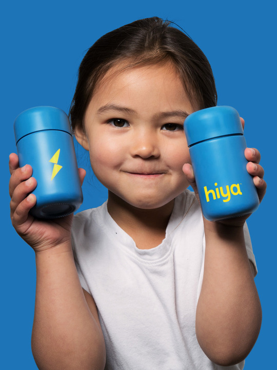 A child holding up two bottles of Hiya Sleep Supplements.