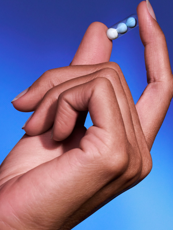 A hand holding up a Ritual Sleep supplement between two fingers.