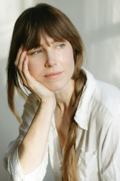 A young woman at home, resting her head on her hand, lost in thought.