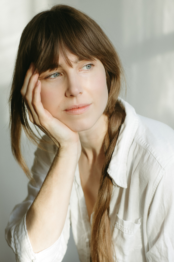 A young woman at home, resting her head on her hand, lost in thought.