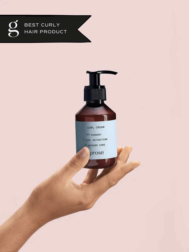 A hand holds Prose curl cream against a pink background. 