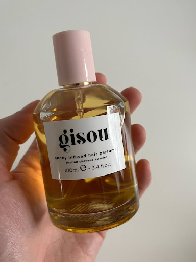 The writer's hand holding the Gisou hair perfume.