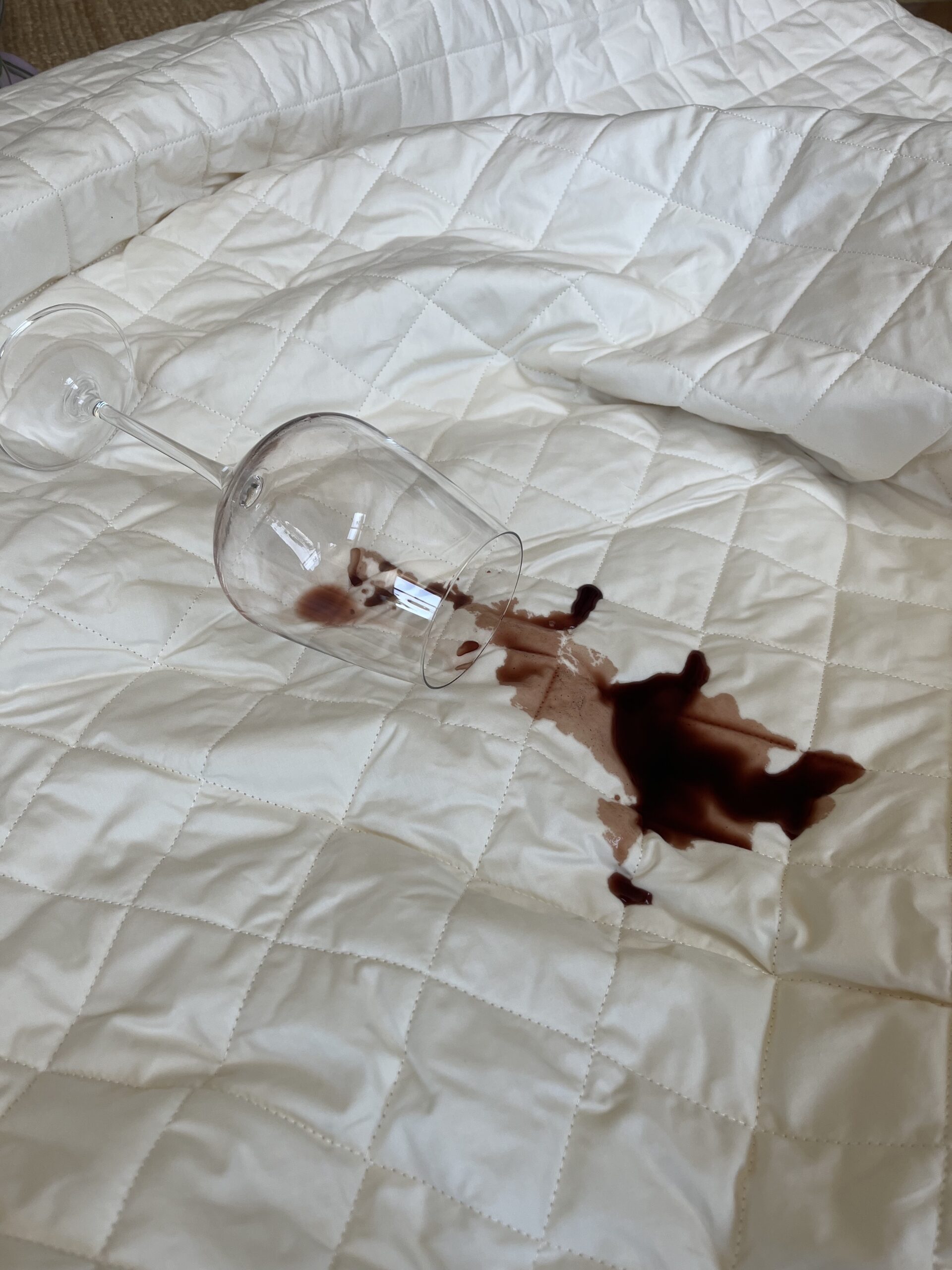 A glass of red wine spilled on a Plushbeds mattress protector. 