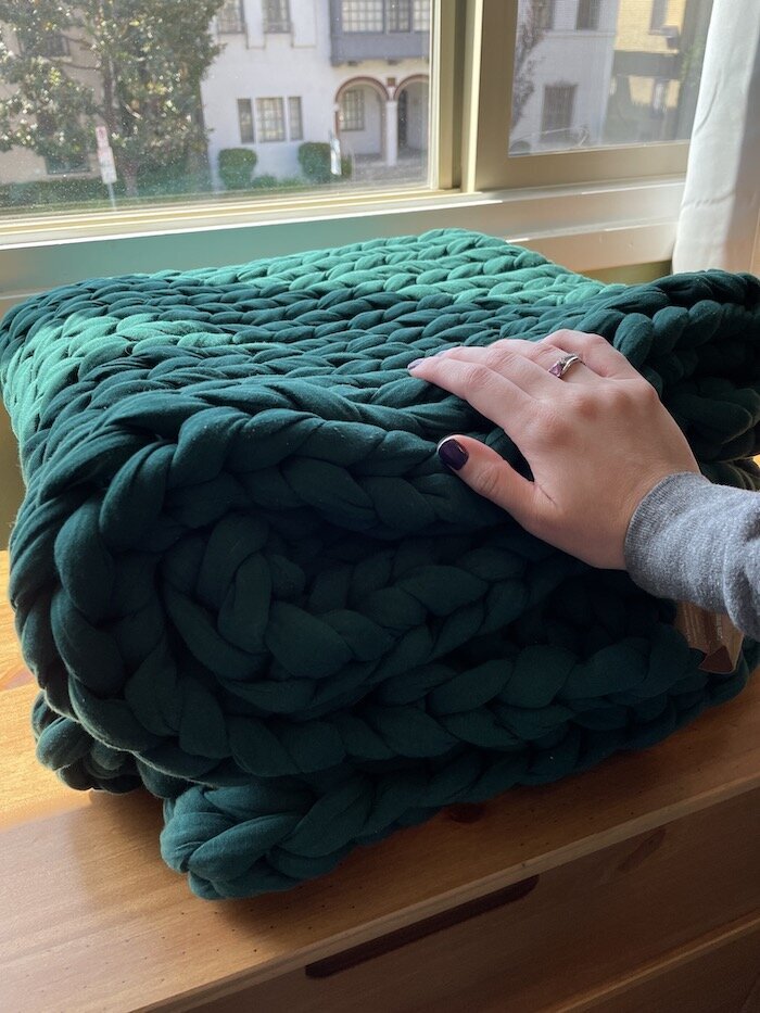 TGT Editor's hand on a green Bearaby Napper blanket.