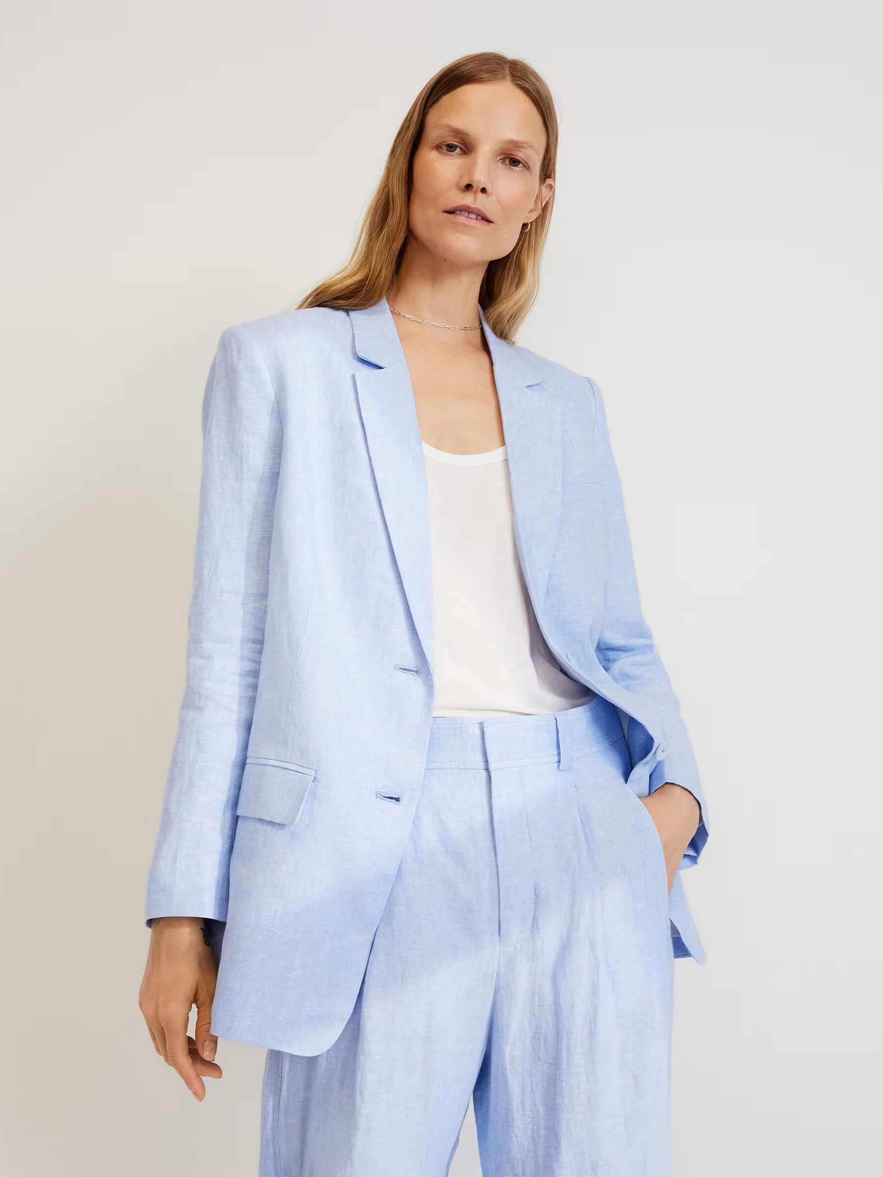 A model wearing a light blue linen pantsuit from Everlane.