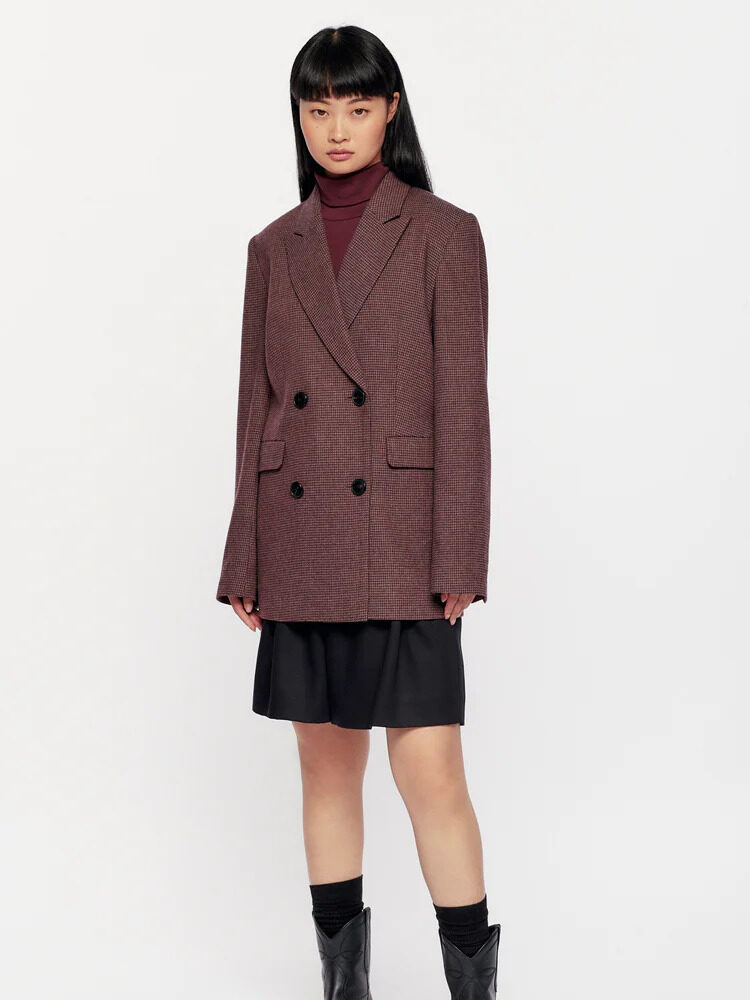 A model wearing a burgundy plaid oversized blazer and black skirt from Kotn.