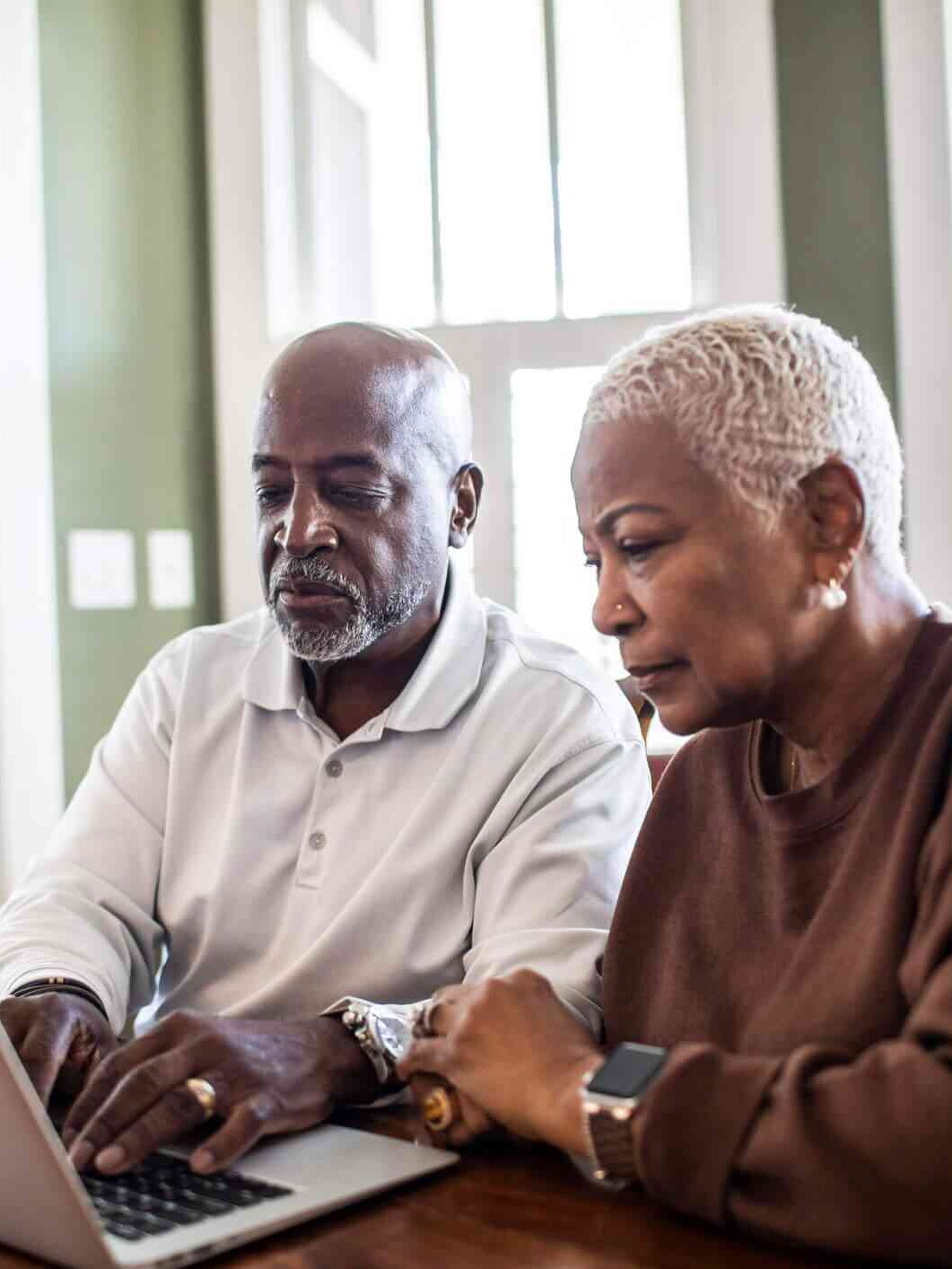 An older couple using a laptop at home.
