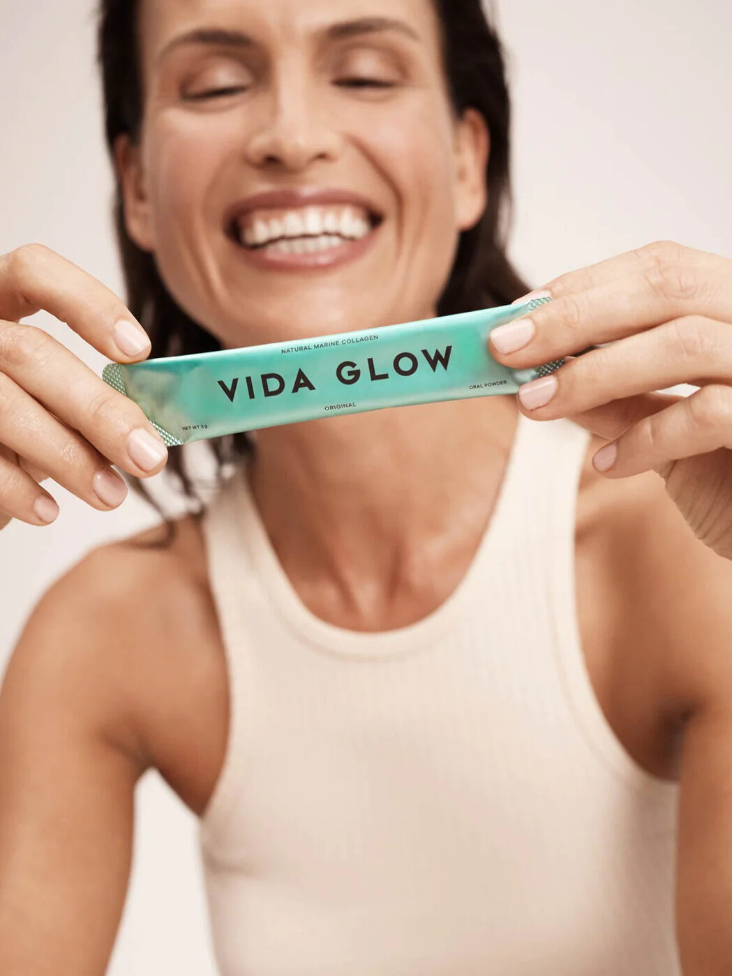 A model holding up a packet of Vida Glow's marine collagen. 