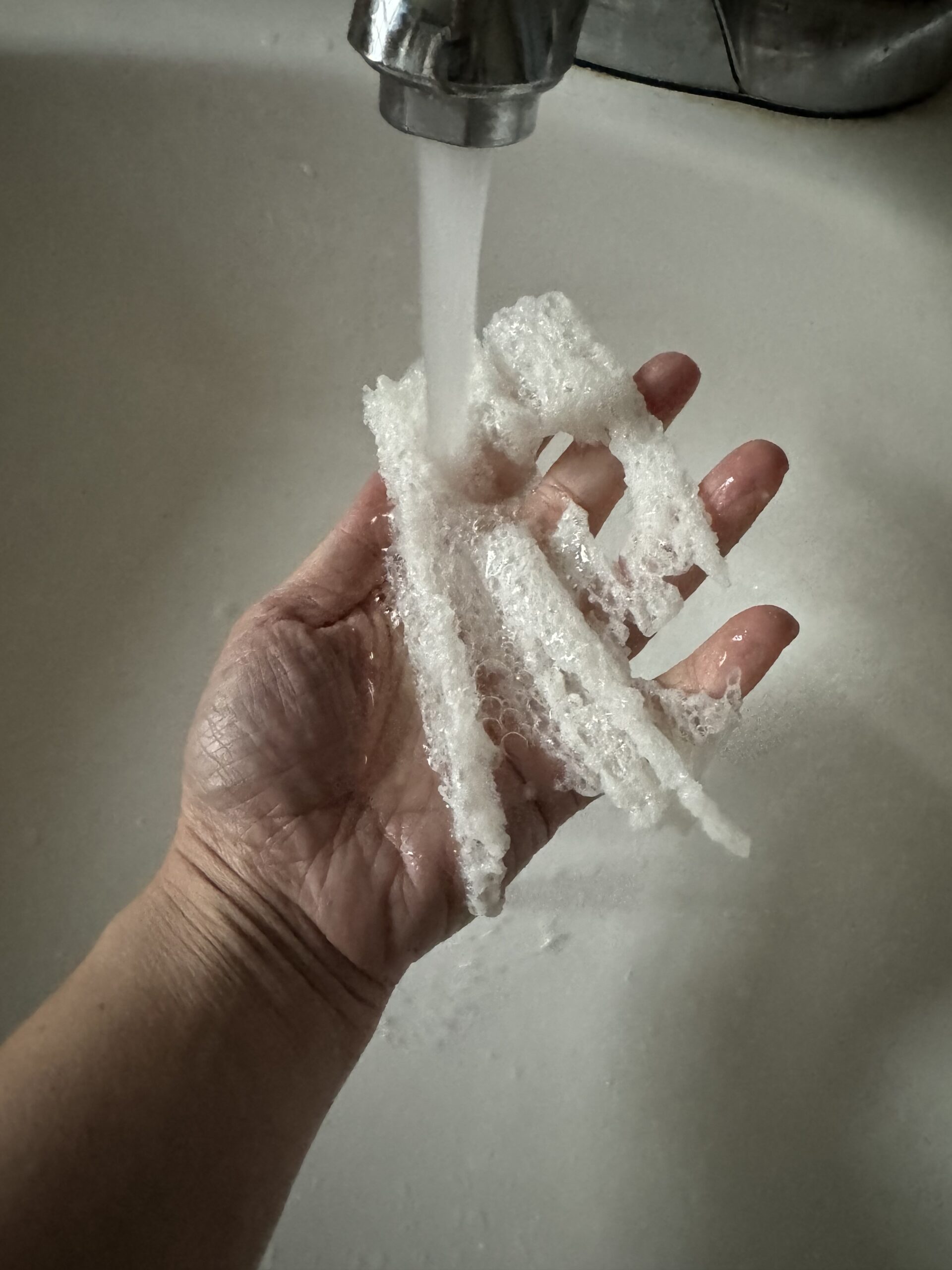 A person washing their hands with soap under a running faucet.