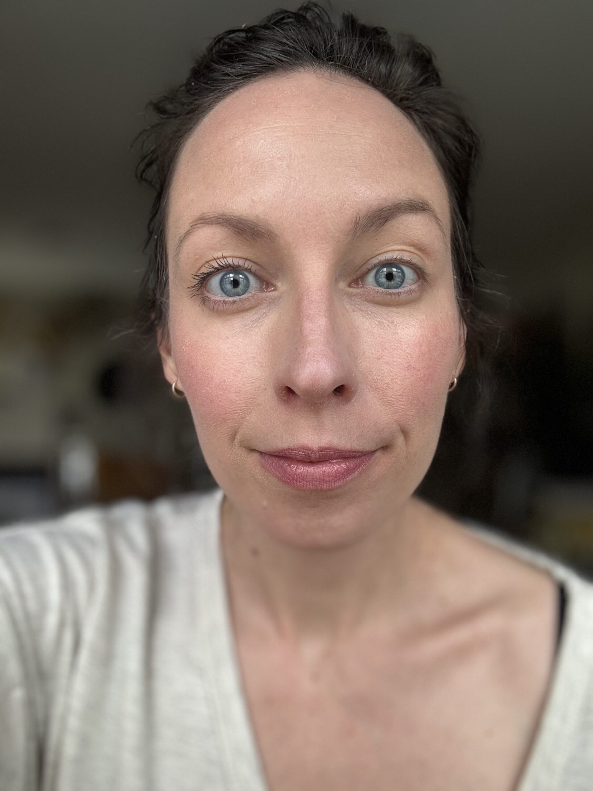 A close-up portrait of a woman with blue eyes and a slight smile.