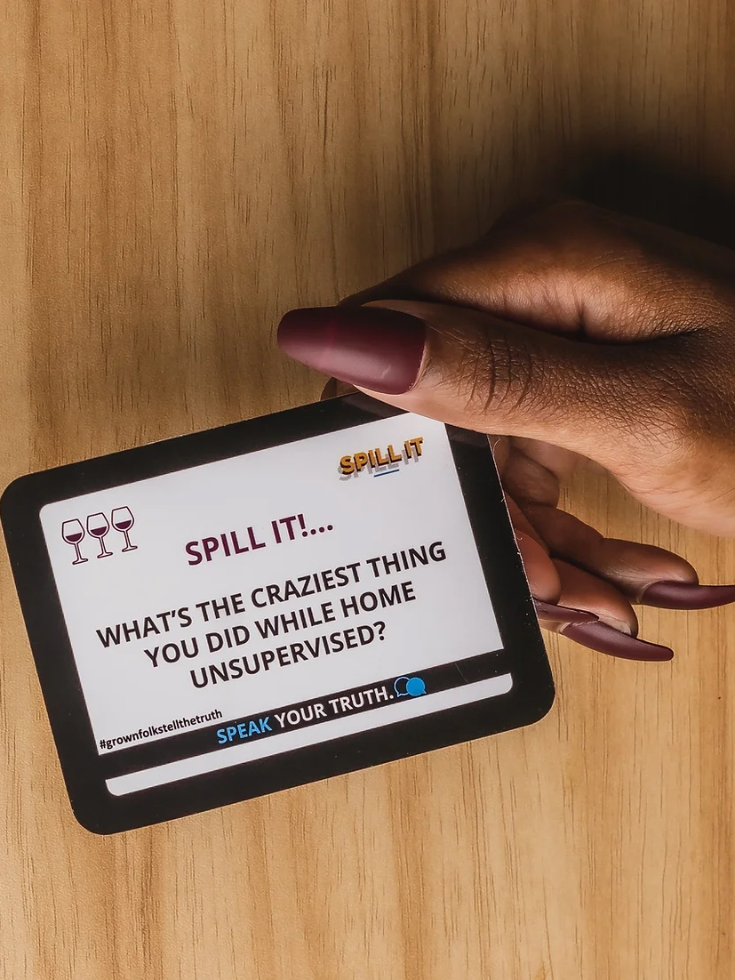 A person holding a card with a prompt asking about the craziest thing done while home unsupervised.