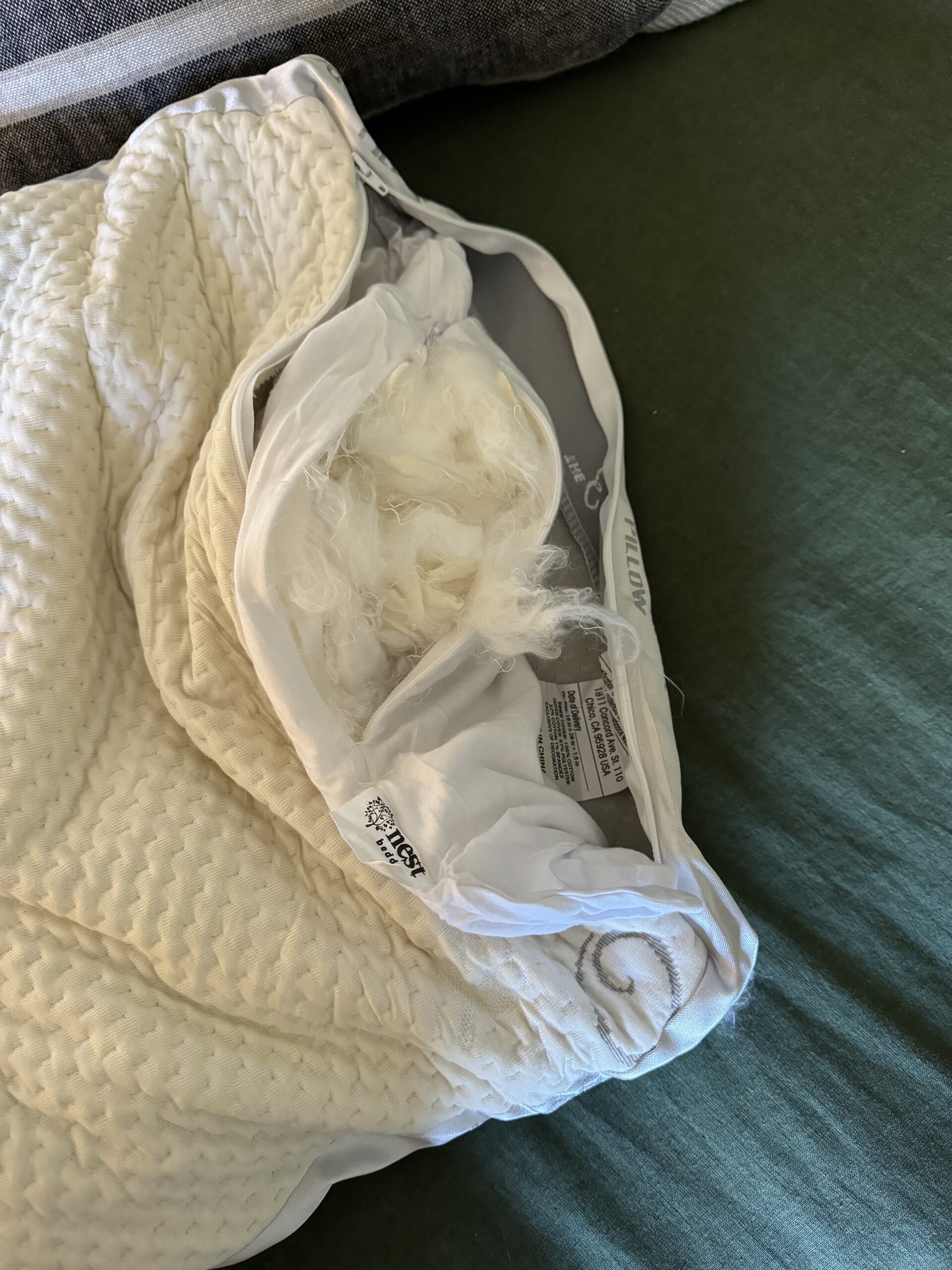 A cushion with its stuffing coming out, placed on a green surface.