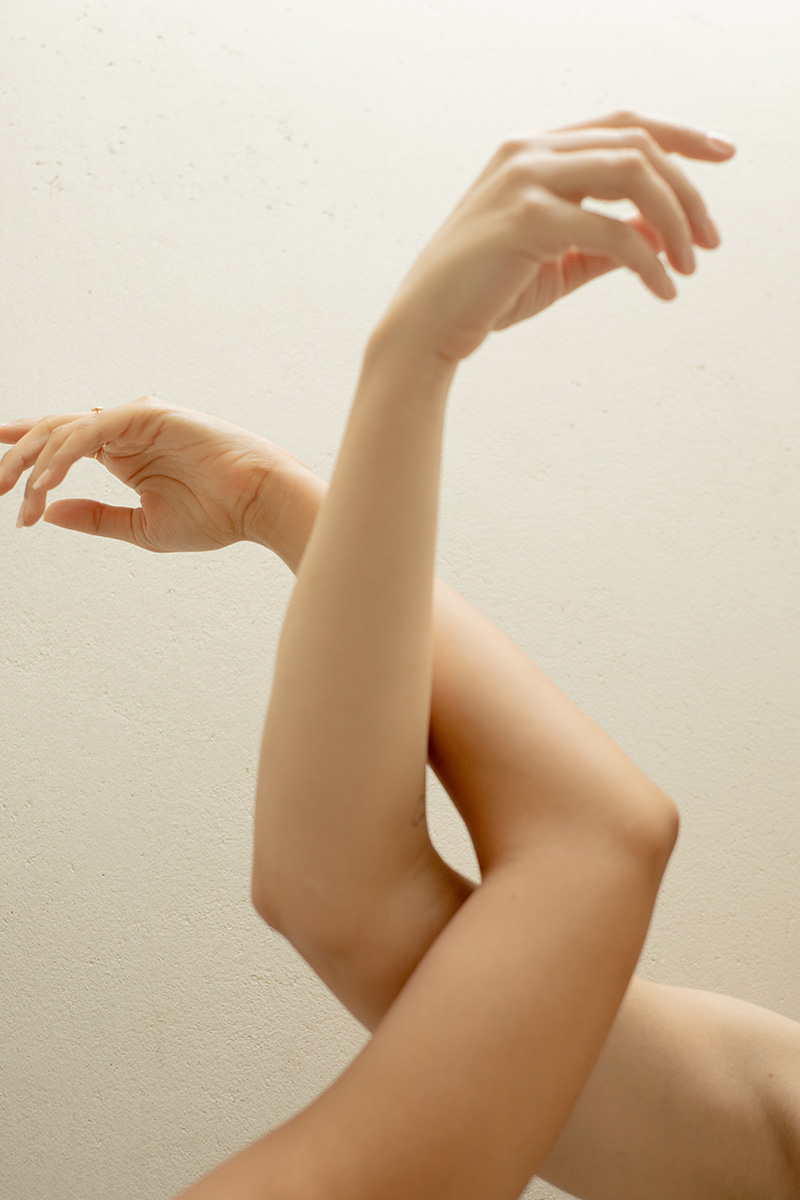 An abstract depiction of a person with a focus on gracefully positioned hands and legs, using a soft, neutral background.