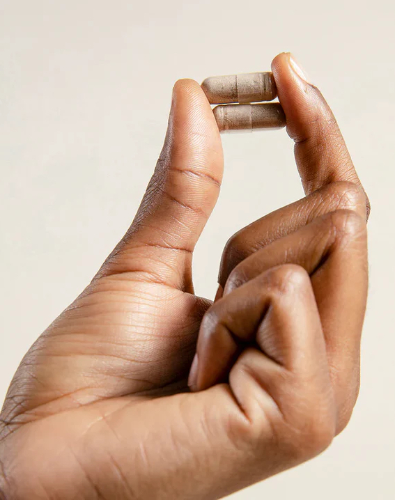 A close-up photo of a person's hand holding a small, cylindrical metallic object between their thumb and index finger.