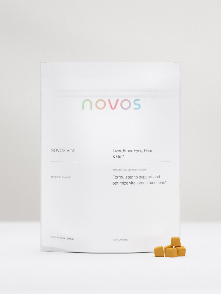 A white package of NOVOS Vital supplements is displayed, with a few yellow gummies in front. The text on the package highlights benefits for liver, brain, eyes, heart, and gut.