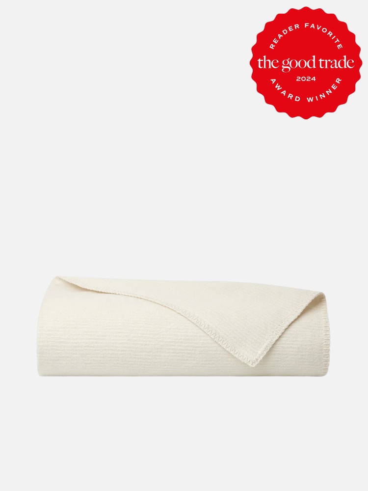 A rolled-up, off-white blanket is displayed against a plain background. A red seal in the top right corner reads "Reader Favorite the good trade 2024 Award Winner.