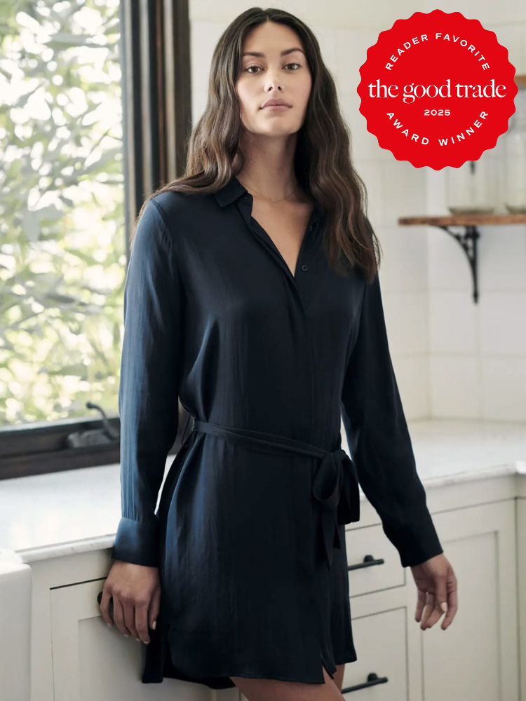 Woman in a dark belted shirt dress stands in a sunlit room. A red badge in the corner reads "Reader Favorite, The Good Trade, 2025 Award Winner.