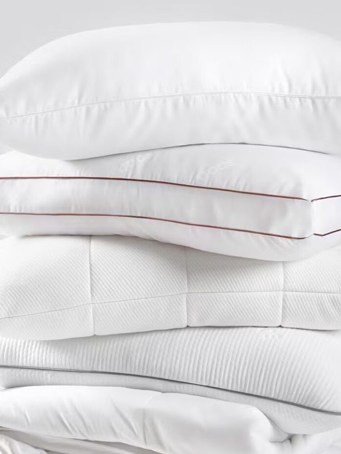 A stack of neatly folded white bedding and pillows against a plain white background.