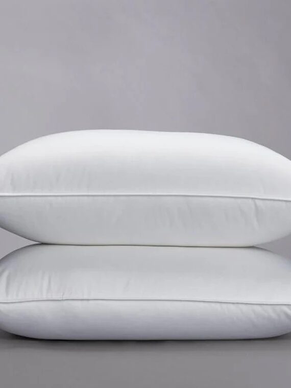 Two white pillows stacked on top of each other against a plain gray background.