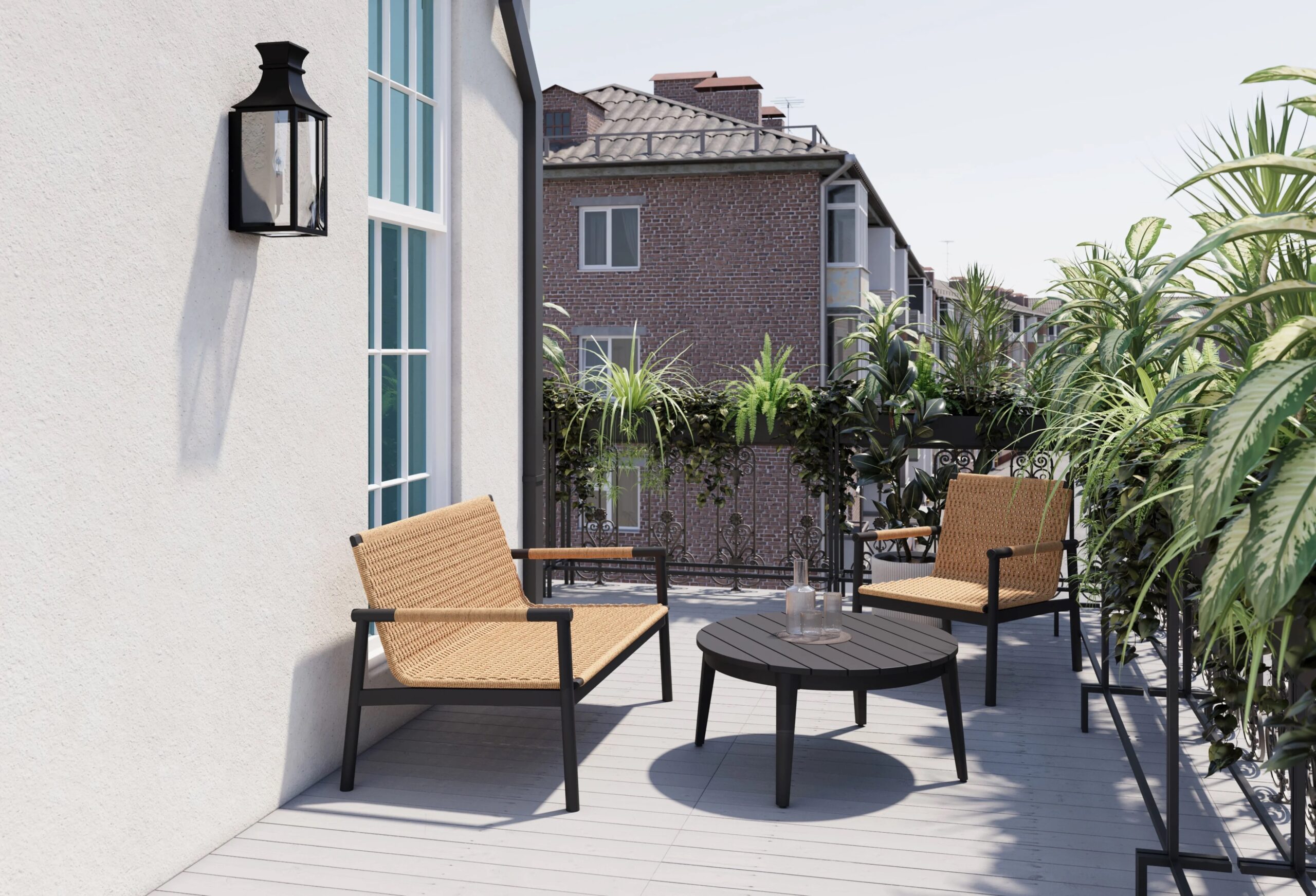 A balcony with two wicker chairs, a round black table with water glasses, potted plants along the railing, and buildings visible in the background.