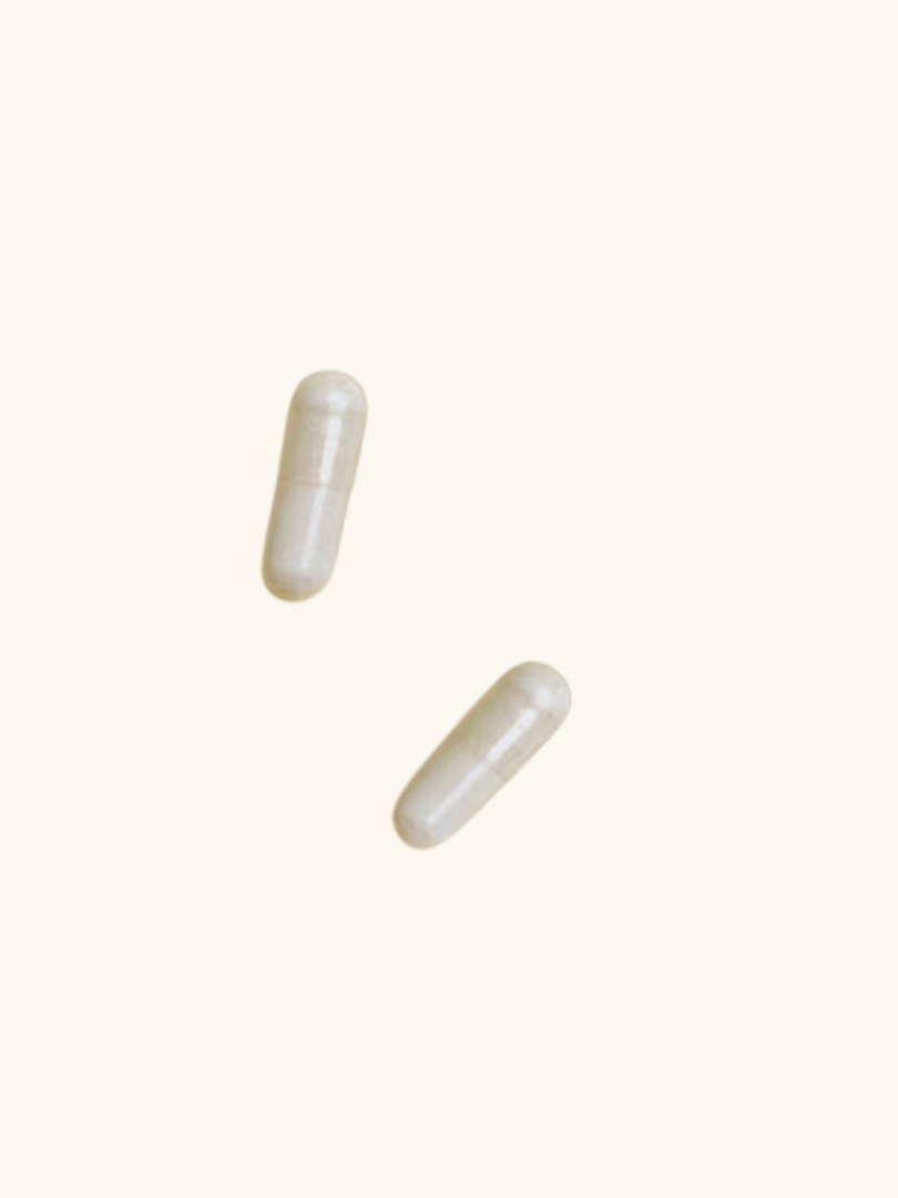 Two white capsules are positioned against a plain, pale background.