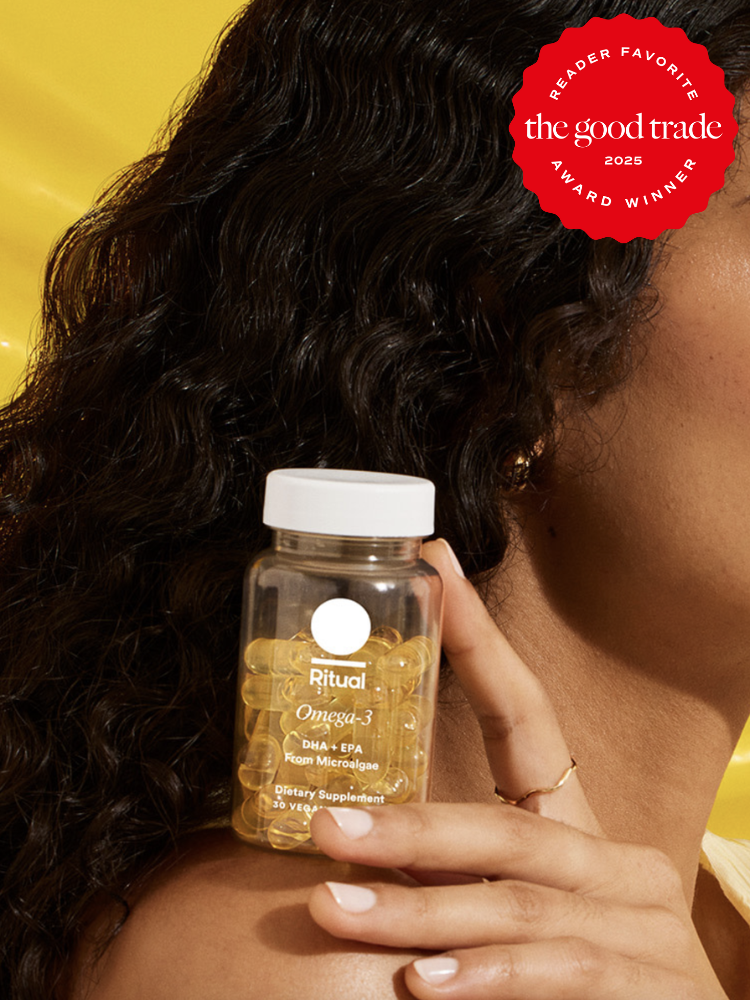 A person holds a bottle of Ritual Omega-3 supplements against a yellow background. The bottle contains soft gel capsules. A "Reader Favorite" award badge is displayed in the corner.