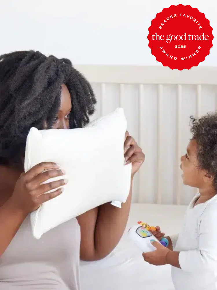 Woman plays peekaboo with a pillow with a child holding a toy. Red award badge in corner says, "Reader Favorite, The Good Trade, 2025 Award Winner.