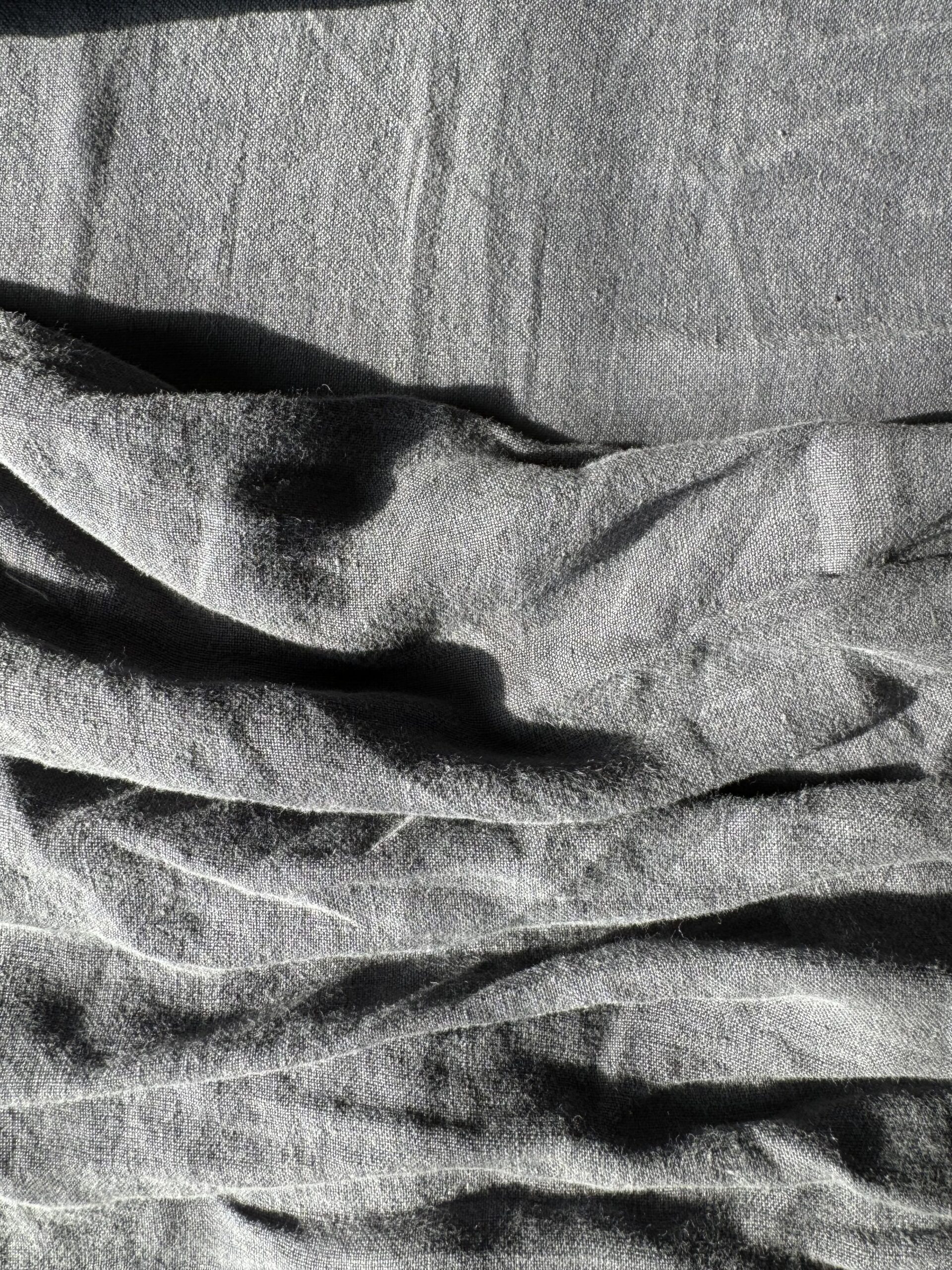 Crinkled grey fabric with visible folds and creases, captured in natural lighting.