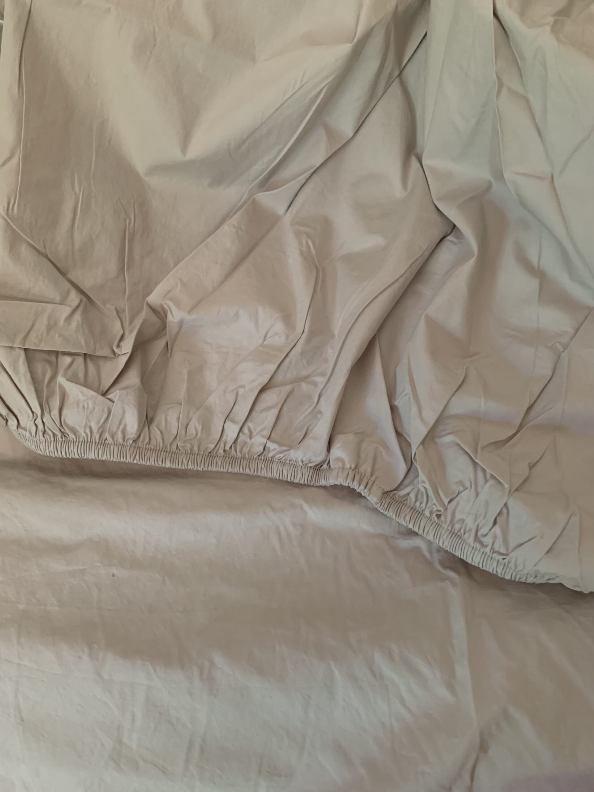 Wrinkled beige sheets with gathered edges are partially folded, revealing a textured surface underneath.
