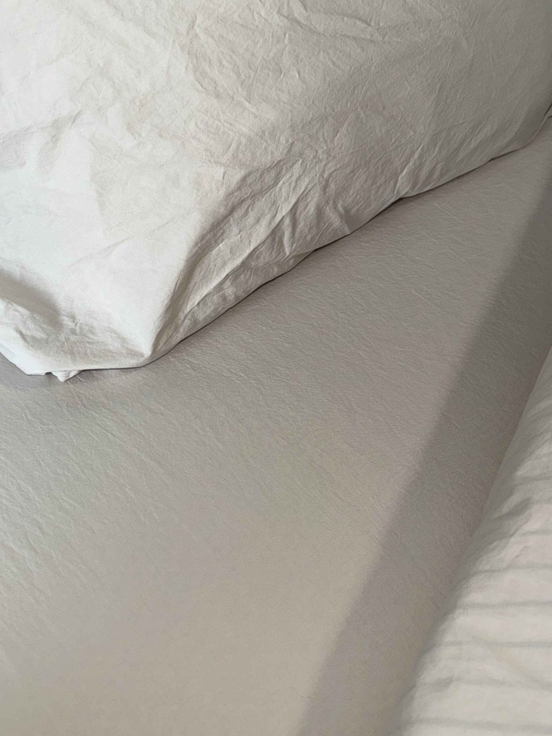 A close-up of a neatly made bed with white sheets and pillowcases.